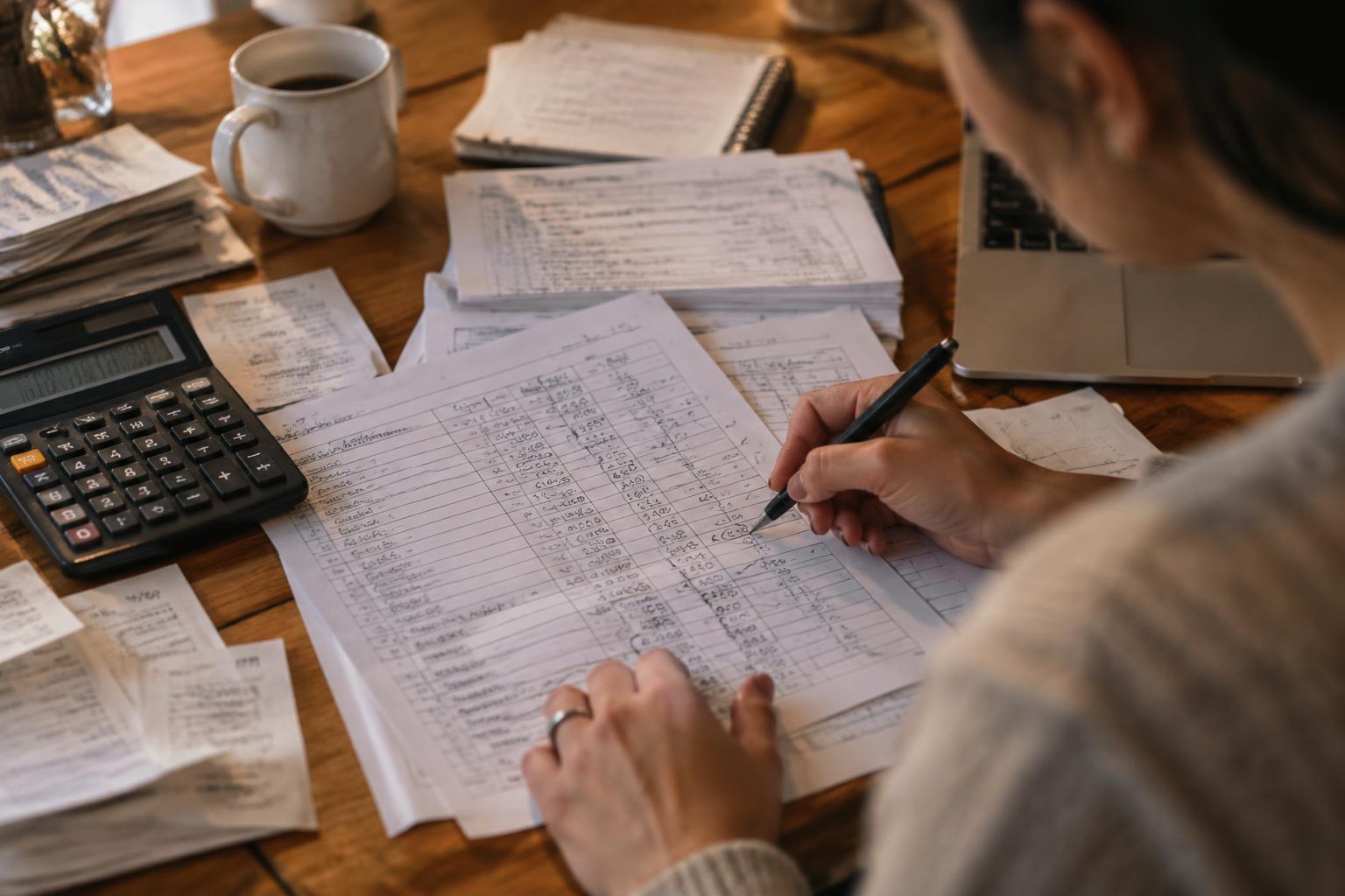 Handwritten timesheets and invoices on a desk with a calculator and pencilled question marks